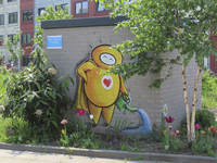 907100 Afbeelding van het graffitifiguurtje 'The Friendly Hero' van Mr. Kubus dat de plantjes giet, op een gebouwtje op ...